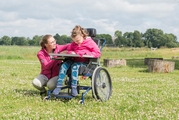 Working with disability / A disabled child in a wheelchair relaxing outside with a special needs carer.