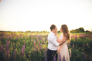 Young wedding couple walking on field with flowers