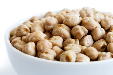 Detail of dried chickpeas in white bowl on white.