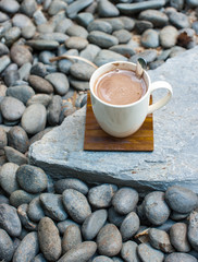 white cup of coffee against black stones