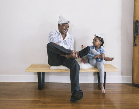 African American grandfather and granddaughter playing on bench