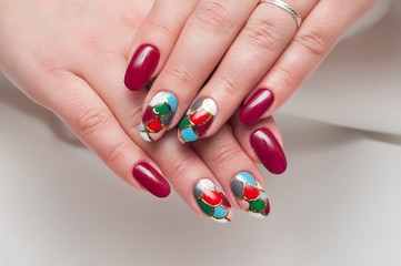 Obraz na płótnie Canvas maroon trim long nails with a mosaic of different colors and gold