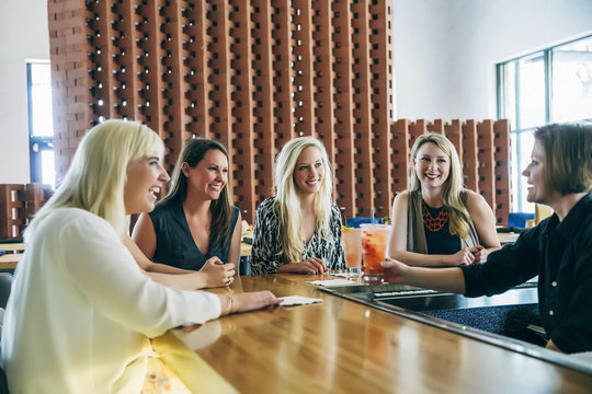 Caucasian bartender serving cocktail to women