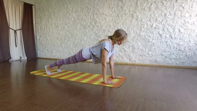 The young blonde girl practicing yoga in the hall. Pose of cobra. Pose of plank. 4K