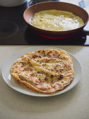Pancakes on a plate and pancake on a frying pan.