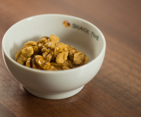 Walnuts in white bowl on wood background