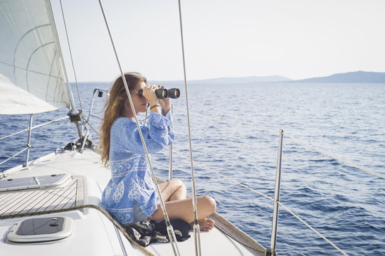 Caucasian woman using binoculars on boat deck