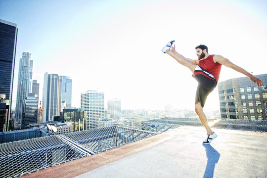 Caucasian man kicking on urban rooftop