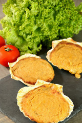 Galician scallops on a slate dish. Background: green salad and tomatoes.