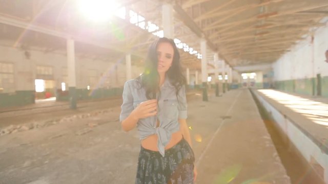 Girl dancing in an abandoned factory in the sun, and the dust raised