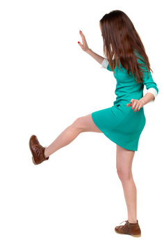 skinny woman funny fights waving his arms and legs. Isolated over white background. Long-haired brunette in a green dress kicks.