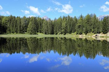 Fototapeta na wymiar Bergsee mit Wald und Wolken