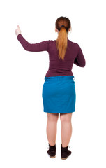 Back view of  woman thumbs up. Rear view people collection. backside view of person. Isolated over white background. The red-haired girl in a blue skirt shows thumb up.