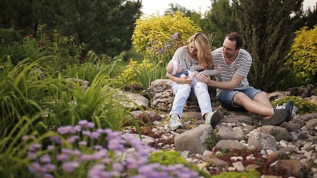 Young parents with a daughter play in the park at sunset