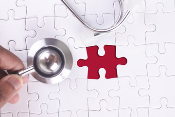 Medical Concept - A doctor holding a Stethoscope on  missing puzzle