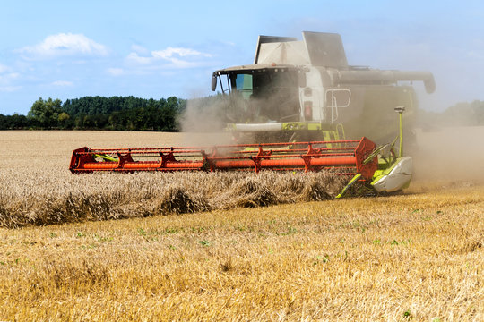 combine harvester working with dust on the field 