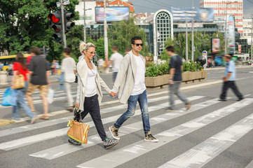Fashionable couple crossing road at pedestrian zebra crossing