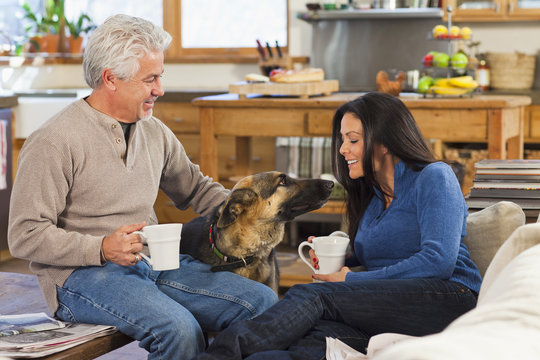 Hispanic couple petting dog in living room