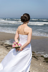 Fototapeta na wymiar bride at Sea / Bride in white dress looks at the Baltic Sea