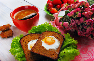 Cup of coffe and two fried eggs in toast on the salad two stars