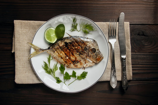 Grilled fish (Vomer) lime ,dill,parsley on the white plate with