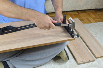 Hammering a plastic part on a drawer of a shoe cabinet