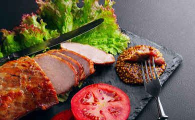 Baked pork fillet, rings of tomato leaf of salad, french mustard