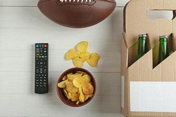 TV remote control with ball, snack and beer on white background
