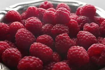 Heap of fresh raspberry on plate, closeup