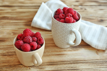 Fresh raspberry in cups on wooden table