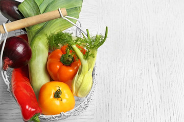 Basket with fresh vegetables on wooden background