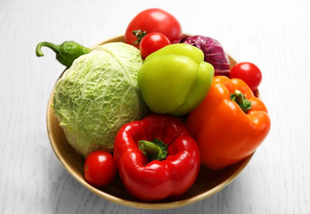 Plate with fresh vegetables on wooden background