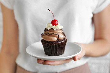Woman holding cupcake with berries, closeup