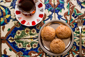 Turkish Dessert Kemalpasa with Tea on a Ottoman Pattern Surface.