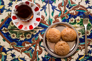 Turkish Dessert Kemalpasa with Tea on a Ottoman Pattern Surface.