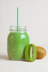 Kiwi smoothie in a jar on a white wooden table.