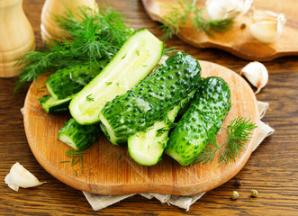 Freshly-salted cucumbers on a board with garlic and herbs