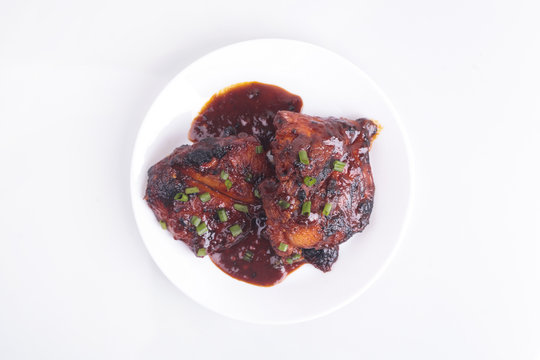 Grilled chicken or ayam golek on white plate, white background.