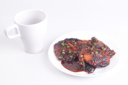 Grilled chicken or ayam golek on white plate, white background.