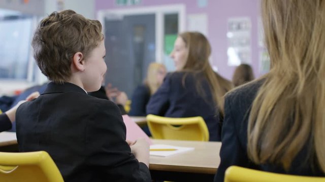  Young students talking & giggling in school classroom.