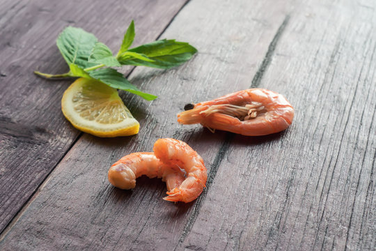 Boiled shrimps with lemon and mint leaves on wooden table