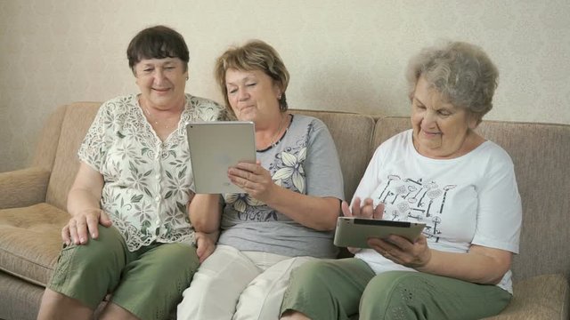 Grandmothers look at photos using digital tablets