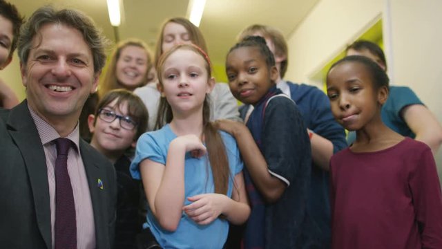  Happy teacher & pupils pose for selfie in school hallway