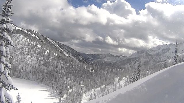 View of mountain peaks and an iced lake covered in deep snow, while ascending with a snow cat during a day of cat skiing. Location: Nelson, BC.
