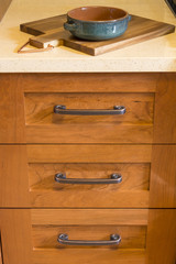 Close-up detail of high quality cherry wood cabinets with bronze cabinet hardware drawer pulls & quartz countertops in contemporary upscale home kitchen interior