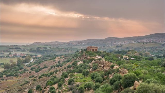 Sunset timelapse of Valley of temples in Agrigento in Sicily with flying clouds and night illumination.