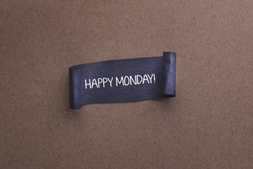 Black papper with HAPPY MONDAY word on wooden background.