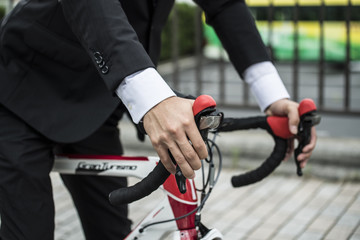 The hands of the businessman is holding a bicycle handle
