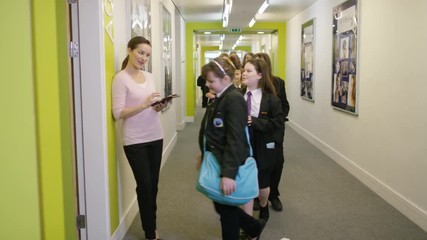  Young school children enter classroom for a lesson as teacher waits by door