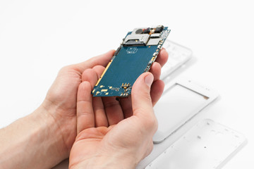 Smartphone dismantling on white background. Repairman hands holding telephone in hands. Disassembled phone in repair service, white background, electronics recovery concept